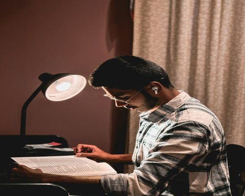 A person reading a book with a comfortable desk lamp