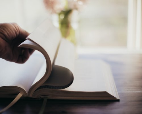 Hands turning pages of a book with soft natural lighting